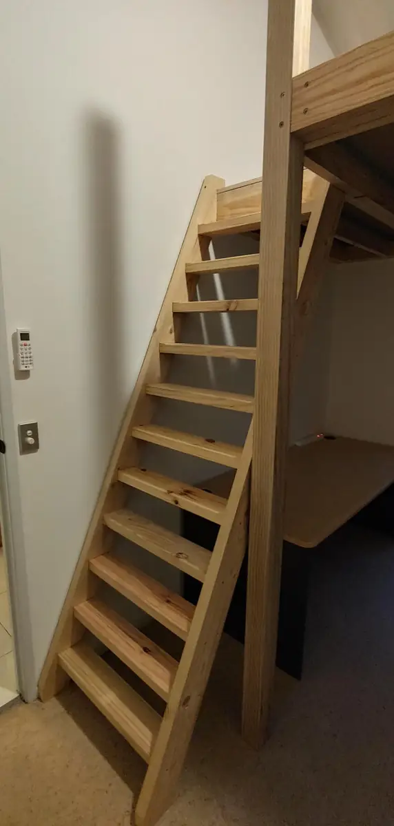 Timber staircase up to a loft bed