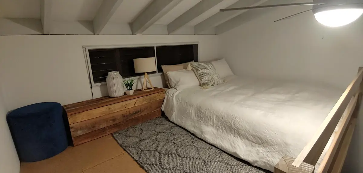 Finished loft bedroom, styled with a bed and lamp